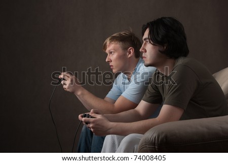 two friends are focused on playing video games on gray background