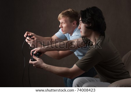 two friends are focused on playing video games on gray background