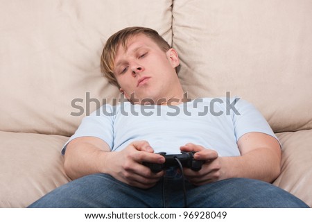 young man gets tired while playing video games on gray background