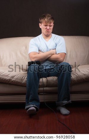 portrait of a sad young man playing video games on gray background