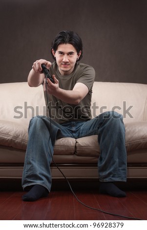 portrait of a young man playing video games on gray background