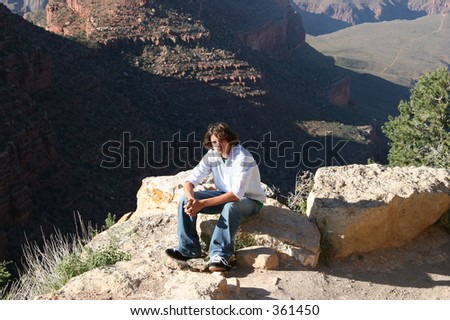 Teenage boy sitting near edge at Grand Canyon.
