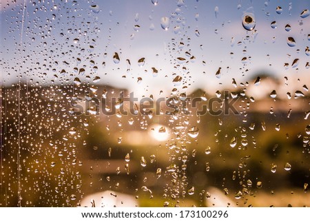 Drop on a glass window and a blurred landscape on the background