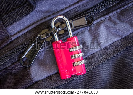 A little red combination padlock locking zippers on luggage
