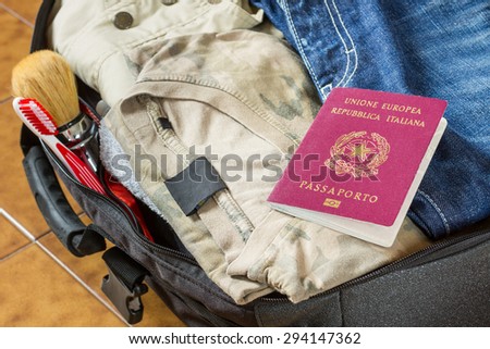 An open suitcase with clothes, personal effects and an italian passport on it