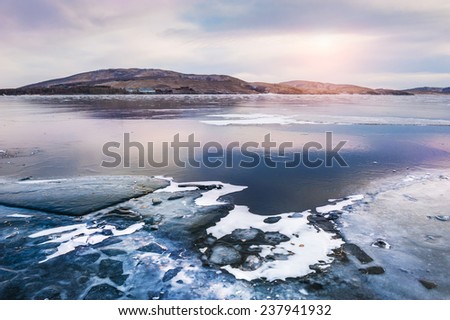 Beautiful winter lake with ice at sunset. Winter landscape