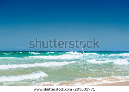 Surfing on the sea coast. Crete island, Greece. Tropical beach with turquoise water and big waves