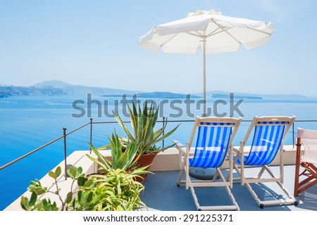 Deck chairs on the terrace with sea view. Santorini island, Greece. Beautiful summer landscape