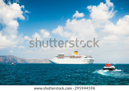 Cruise ship at sea. Turquoise sea and blue sky with clouds. Santorini island, Greece.