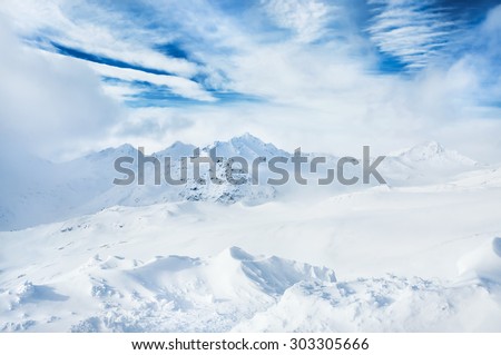 Winter snow-covered mountains and blue sky with white clouds. Beautiful winter landscape