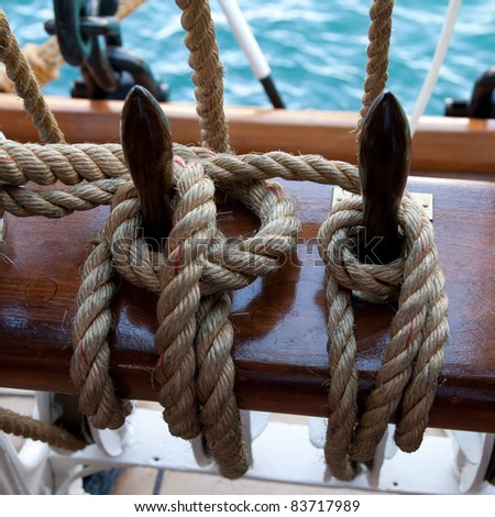 Two ropes control the sails, tied to a wooden beam