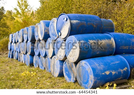A lot of blue barrels deposited somewhere outside.