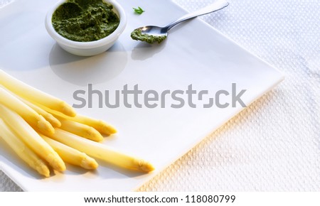 White asparagus and pesto sauce on a white plate