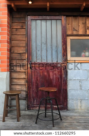 chairs in front old wood door closed with new gold lock on ruin brick wall