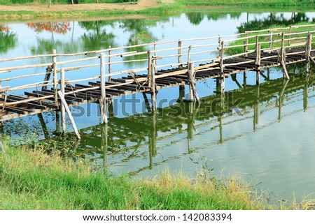 Old unfinished wood bridge over water in a garden