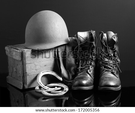 Still life art photography on vintage army helmet jungle boots and horseshoes black and white version