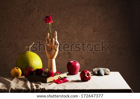 Red rose in wooden hand shows love sign with old book and mixed fruits