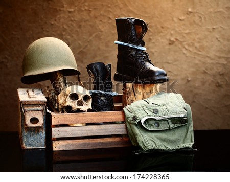 Still life art photography on vintage army concept with helmet jungle boots and metal bullets box pistol and skull