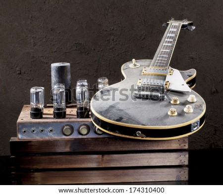 Still life art photography of vintage electric guitar cover with dust and rare vintage valve amplifier on grunge background