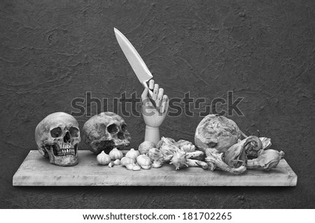 Still life art photography with light painted on human skull and bunched of garlics on wood panel and grunge background black and white version