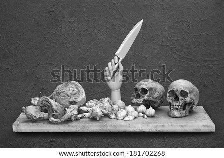 Still life art photography with light painted on human skull and bunched of garlics on wood panel and grunge background