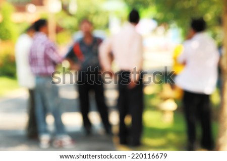 Men standing under trees in the park high key lens blurred without filter unrecognizable faces