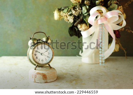 Vintage gold alarm clock with time concept over dried flowers