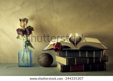 Vintage books and pages love heart with red and dry roses on grunge sand stone table