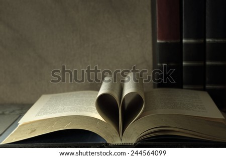 Vintage books and pages love heart sign on grunge sand stone table still life style