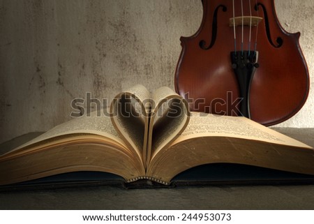 Vintage books and pages love heart sign with violin on grunge sand stone table still life style