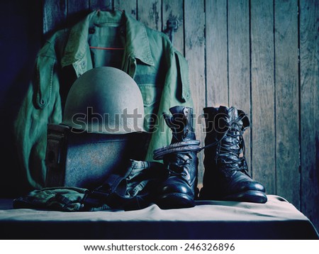 Still life art photography on vintage army jacket field coach helmet jungle boots and metal bullets box