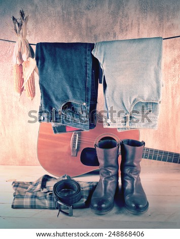 Hanging jeans and corns with shirt and boots over acoustic guitar and grunge background still life style