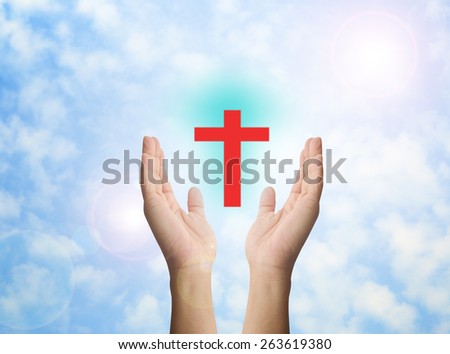 Human hands praying over the red cross and amazing light background