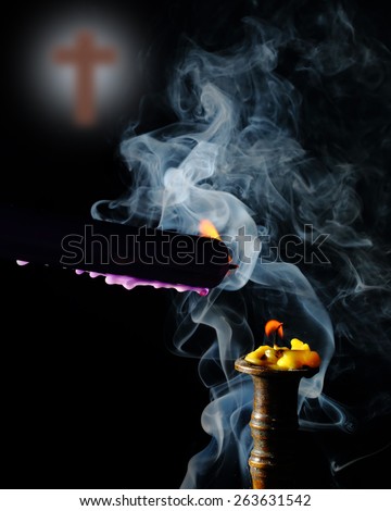 lighting candle to candle on smoke with blur cross backdrop