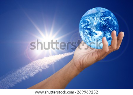 Hand holding global over contrail cloud with blue sky and fairy sparkle sun with flare ?Elements of this image furnished by NASA