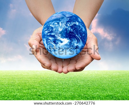 Human hand presenting global earth over blue sky and green grass field Elements of this image furnished by NASA