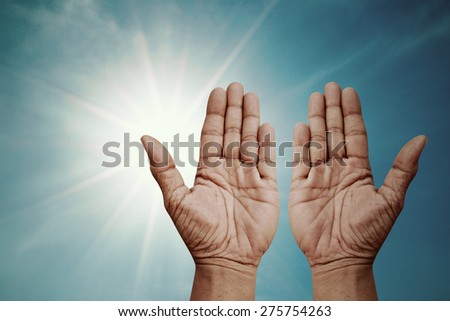 Praying hands over sparkly sun