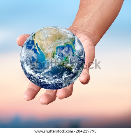 Human hands carrying global Earth over gas clouds and Sun over green glass a World Environment Day Concept Elements of this image furnished by NASA