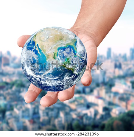 Human hands carrying global Earth over gas clouds and Sun over blurred city a World Environment Day Concept Elements of this image furnished by NASA