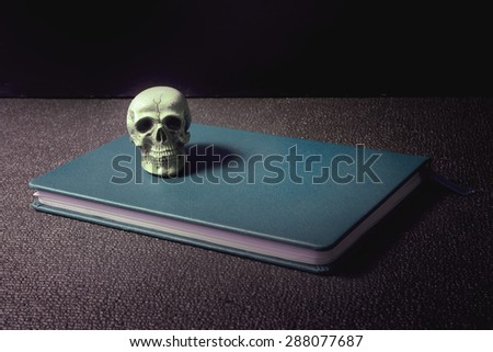 Scary skull on notebook in dark room a still life art wisdom concept