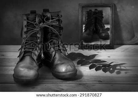 Still life art photography on jungle boots and monochrome wood frame