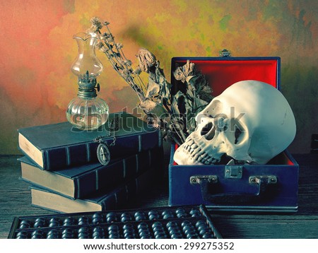 Still life art concept on human in box and properties with skull old book oil lantern abacus and Jesus Christ cross with necklace on old wood floor over grunge background misty blue version