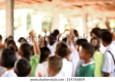 Blur students raised hands up in the canteen