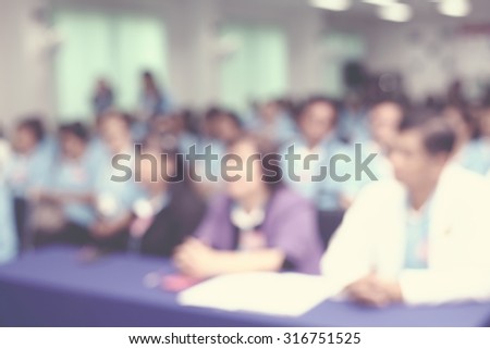Lens blur on crowd sitting in convention seminar room