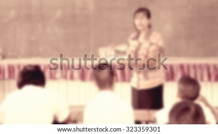 Blur female teacher showing media in hand in front of classroom listening for lecture and school project home work