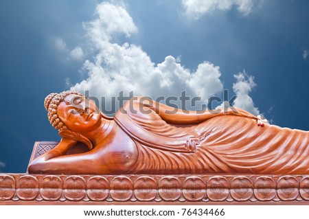 Large wood crafted sleep Buddha image in Thailand isolated on blue sky background.