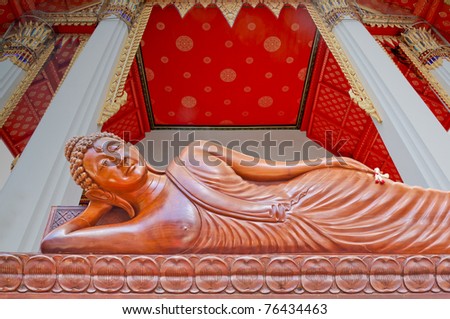 Large wood crafted sleep Buddha image in Thailand isolated on temple roof background.