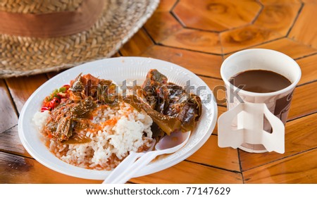 hot soup on streamed white rice and a cup of coffe on solid wood table as fast food