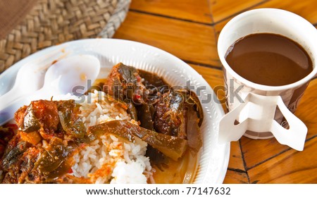 hot soup on streamed white rice and a cup of coffee on solid wood table as fast food