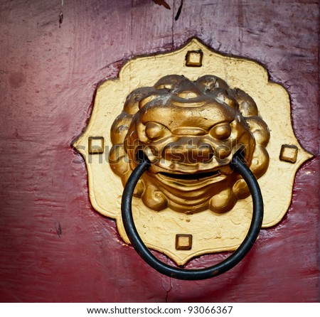 Vintage door handle developing Chinese traditional golden head lion on red wood door